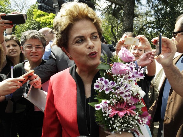 A ex-presidente Dilma Rousseff enfrenta grande tumulto na chegada à Escola Estadual de Ensino Médio Santos Dumont, no bairro Tristeza, em Porto Alegre (RS). Ela recebeu flores de apoiadores (Foto: Itamar Aguiar/Agência Free Lancer/Estadão Conteúdo)