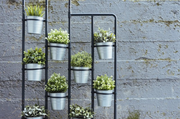 Herb wall featuring aluminium pots, hanging on black frame against a gray brick wall. (Foto: Getty Images)