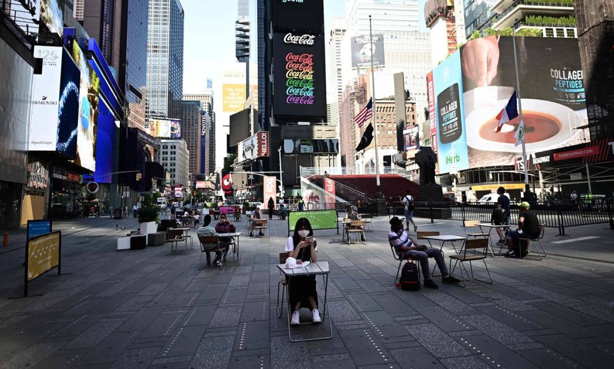 Pessoas se sentam nas mesas, respeitando o distanciamento social, na Times Square. A cidade de Nova York entra na segunda fase da reabertura em 22 de junho. As pessoas voltam a poder comer ao ar livre em restaurantes, e barbearias e salões de beleza também podem abrir com 50% da capacidade — Foto: JOHANNES EISELE / AFP