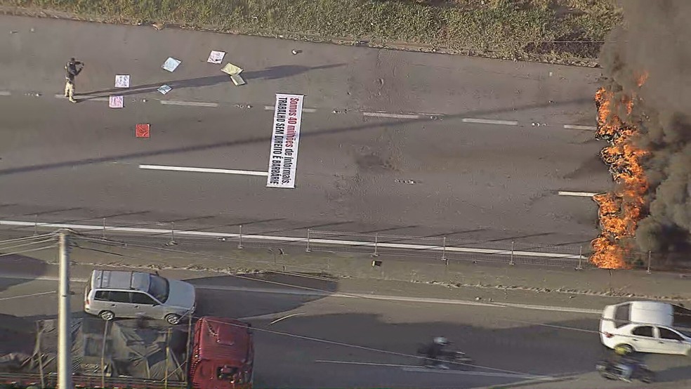 Cartaz com os dizeres "Somos 40 milhões de informais. Trabalho sem direito é barbárie" estirado sobre o asfalto em protesto nesta terça (5) — Foto: Reprodução/TV Globo