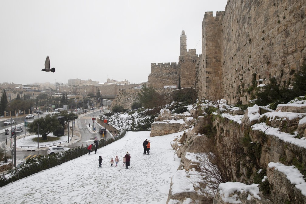 Famílias passeiam na neve próxima aos muros da Cidade Velha de Jerusalém nesta quinta-feira (18) — Foto: Oded Balilty/AP Photo