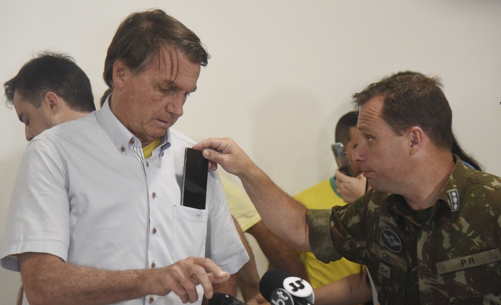 Mauro Cid tira celular do bolso de Jair Bolsonaro no Aeroporto de Guarulhos, em 2022 — Foto: Caio Rocha/iShoot/Agência O Globo