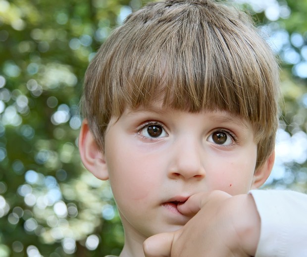 Criança preocupada com o dedo na boca (Foto: Shutterstock)