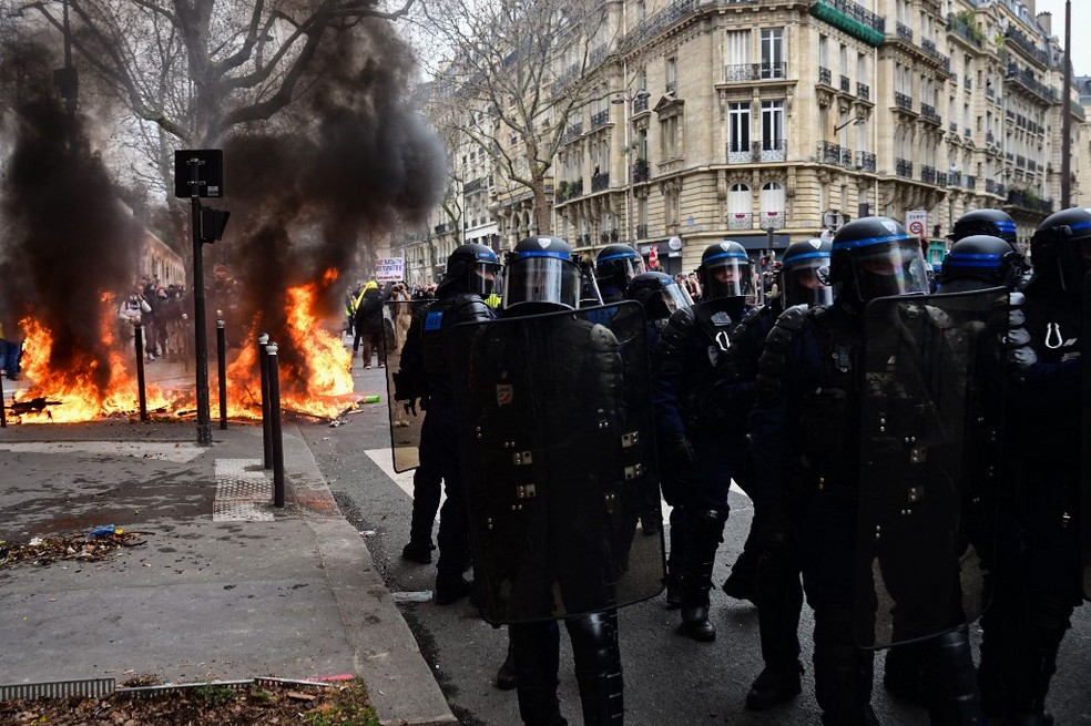 Policiais próximos a fogo ateado durante protestos contra a reforma da previdência, em Paris — Foto: Emmanuel DUNAND / AFP