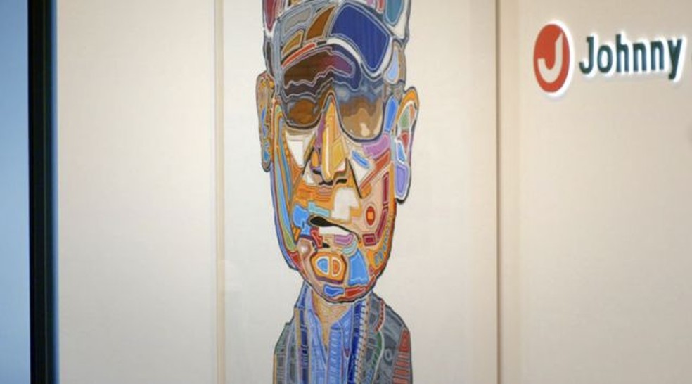 Uma obra de arte do rosto de Johnny Kitagawa está pendurada na recepção principal da Johnny & Associates — Foto: BBC
