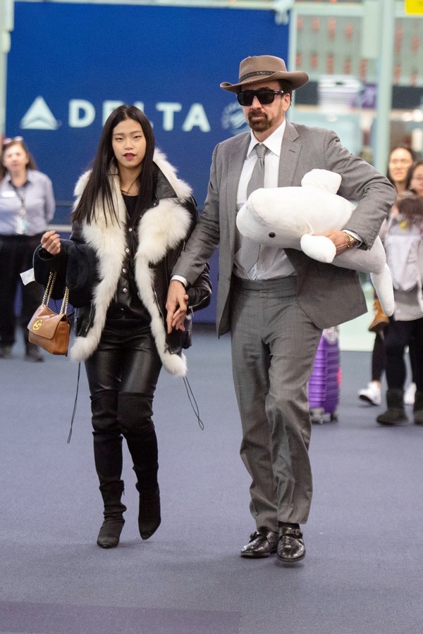 *EXCLUSIVE* New York, NY  - A well dressed Nicolas Cage holds hands his new girlfriend Riko Shibata while carrying a beluga whale plush toy from the Atlanta Aquarium.  The pair looked to be in good spirits upon their arrival at JFK Airport in New York Cit (Foto: BACKGRID)