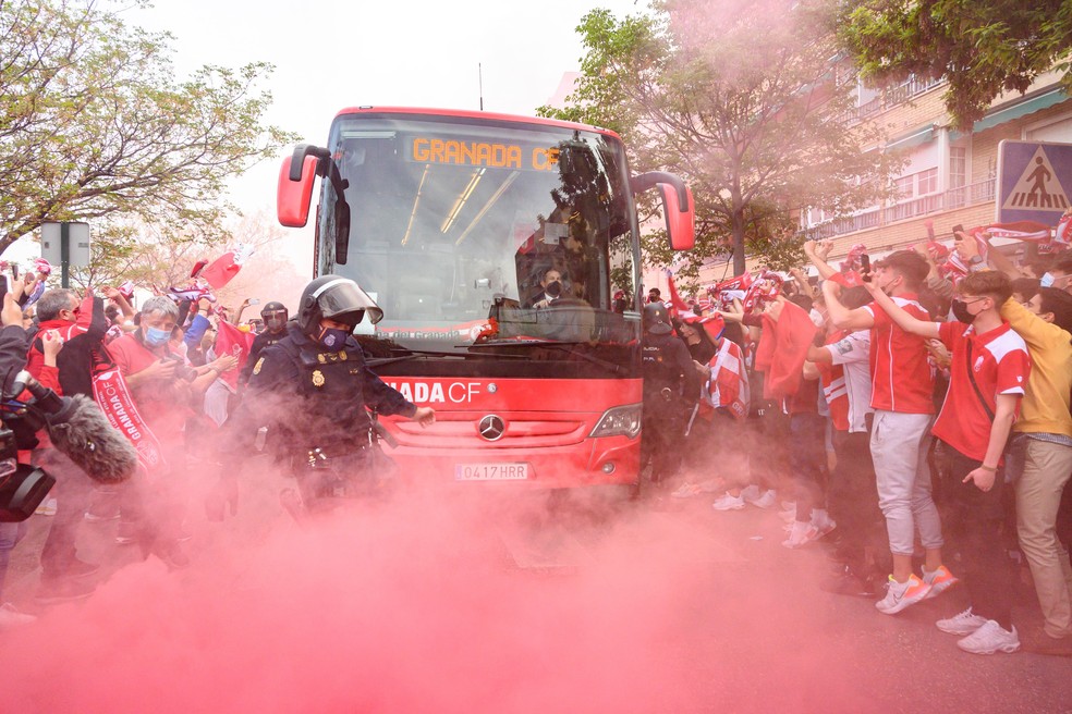 Ônibus do Granada passa em meio a fumaça e tentativa de isolamento policial de torcedores nas ruas de Granada — Foto: EFE/ Miguel Ángel Molina