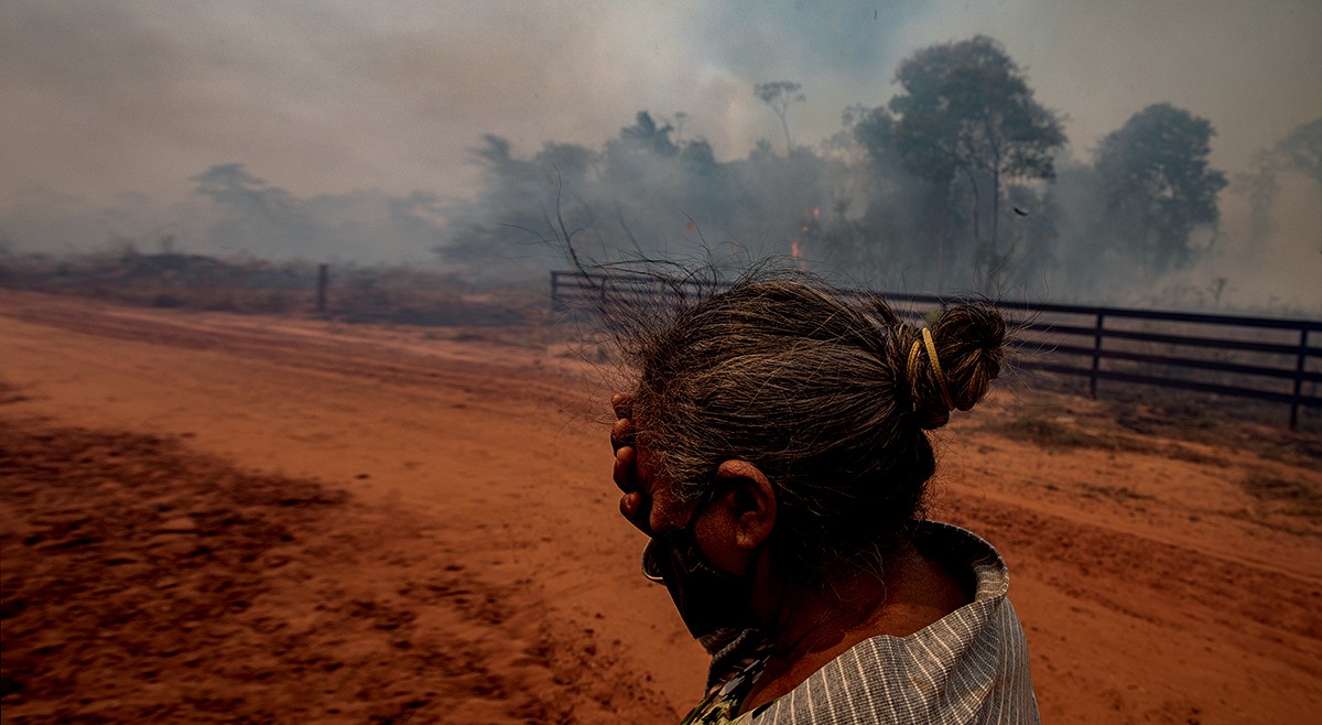 Moradora do assentamento 12 de outubro chega perto do fogo que já durava dias (Foto: Fernanda Liguabue e Victor Moriyama)