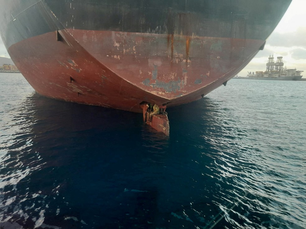 Três migrantes clandestinos são vistos na lâmina do leme do petroleiro Althini II depois de viajarem da Nigéria e antes de serem resgatados pela guarda costeira espanhola, próximo ao porto de Las Palma, nas Ilhas Canárias, na Espanha, em 28 de novembro de 2022 — Foto: Salvamento Maritimo via Reuters