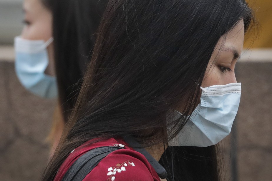 Mulheres usando máscaras contra covid-19 caminham próximas em Pequim, na China