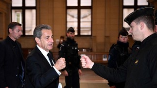 Ex-presidente francês Nicolas Sarkozy cumprimenta policial ao chegar ao tribunal no terceiro dia da audiência de apelação do julgamento por corrupção no tribunal de Paris — Foto: EMMANUEL DUNAND/AFP
