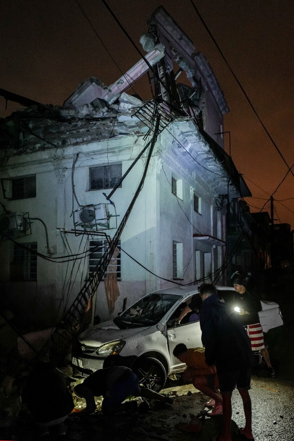 Cubamos tentam nesta segunda-feira (28) recuperar carro danificado após passagem de tornado em Havana — Foto: Adalberto Roque/ AFP