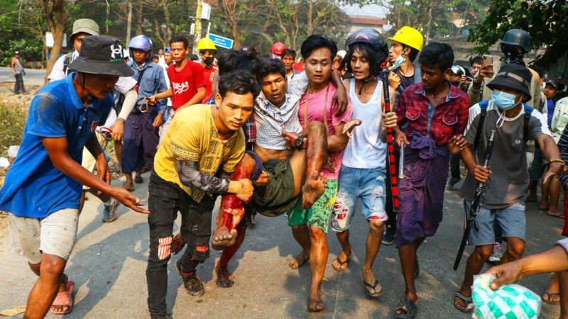 Homem ferido é levado até um local seguro durante manifestação contra os militares em Yangon — março de 2021 (Foto: Getty Images via BBC News)