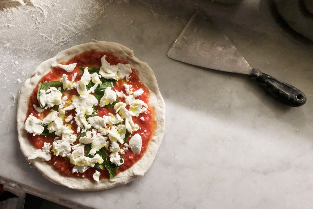 Uma pizza marguerita sendo preparada no balcão da Sorbillo, em Nápoles, uma das melhores pizzarias do mundo (Foto: Getty Images / Mario Laporta)