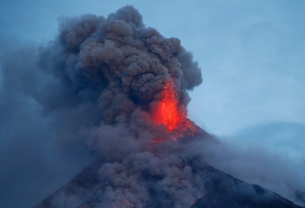 O vulcão Mayon expele lava durante uma erupção esporadica no início desta quinta (25) visto de Legazpi, nas Filipinas. Mais de 74 mil pessoas estão em dezenas de abrigos de emergência enquanto o vulcão continua soltando lava, cinzas, gases superaquecidos e pedras (Foto: Bullit Marquez/AP)