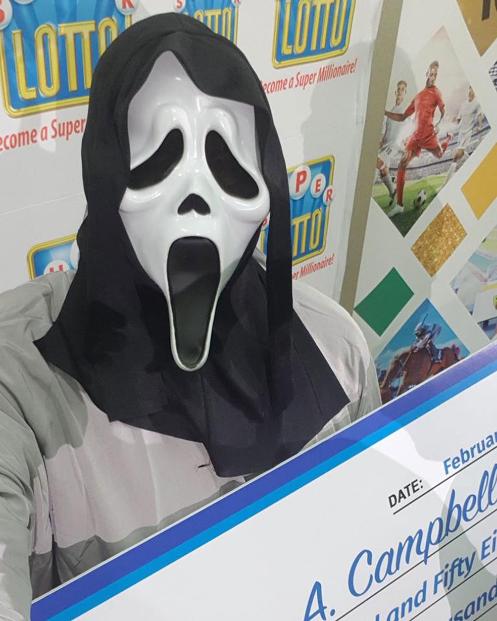 Ganhador de loteria recebe prêmio com máscara do Pânico para não ser identificado na Jamaica — Foto: Supreme Ventures Ltd./Facebook