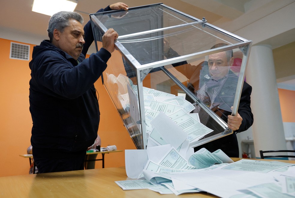 Homens esvaziam urna com votos sobre anexação da região de Donetsk à Rússia — Foto: Alexander Ermochenko/REUTERS