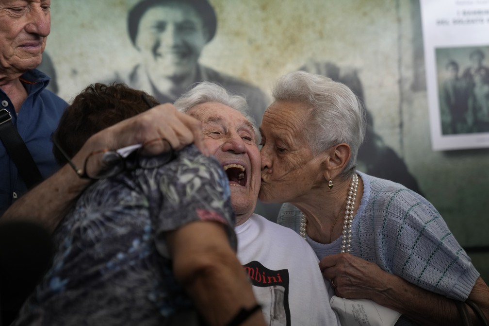 Martin Adler, ex-soldado da Segunda Guerra, recebe um beijo das irmãs Mafalda e Giuliana Naldi — Foto: Antonio Calanni/AP