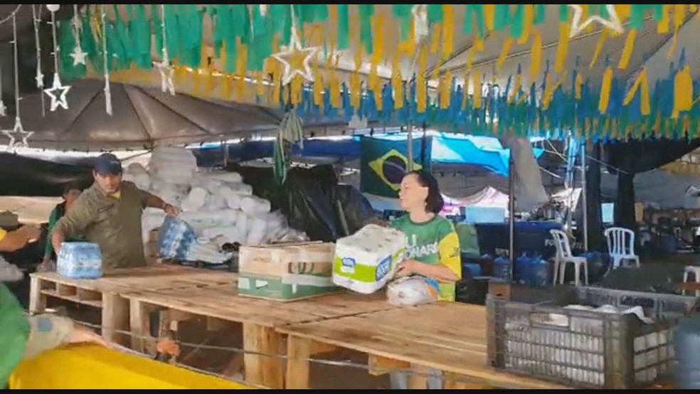 Bolsonaristas manuseiam água e papel higiênico em acampamento em Brasília — Foto: TV Globo/Reprodução