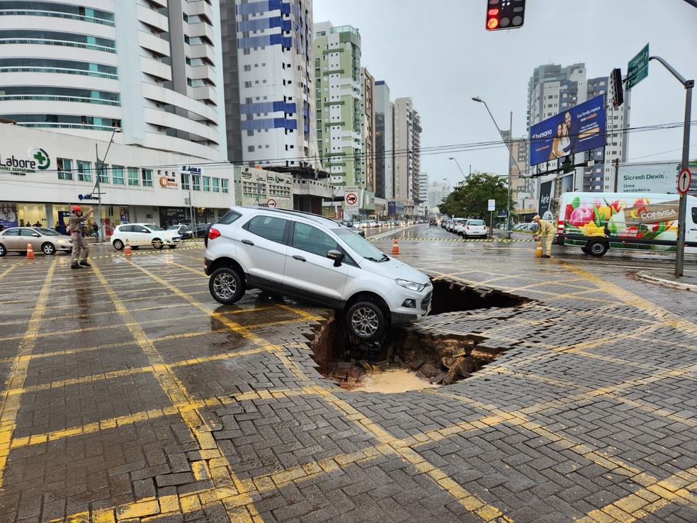 Carro fica "pendura" em cratera que se formou em avenida de Maringá — Foto: Corpo de Bombeiros/reprodução