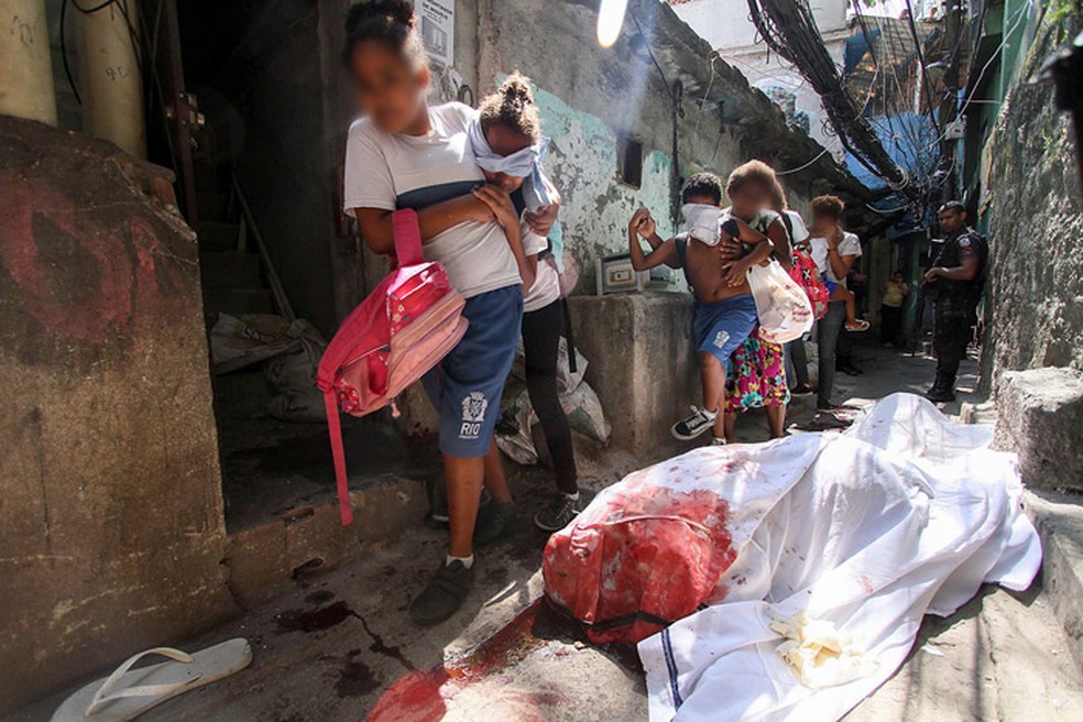 CrianÃ§as com olhos vendados sÃ£o carregadas em viela na Rocinha ao lado de cadÃ¡veres. Registro foi feito no dia 9 de outubro de 2017 (Foto: JosÃ© Lucena/Futura Press/EstadÃ£o ConteÃºdo)