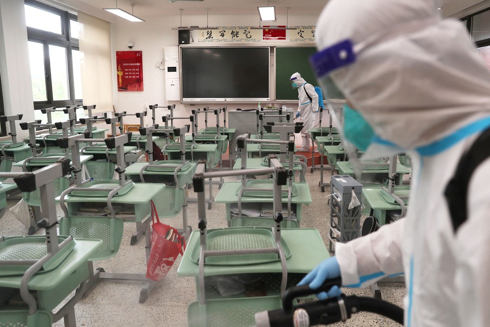 Trabalhadores em trajes de proteção desinfetam uma sala de aula em uma escola para se preparar para a retomada das aulas após surto de Covid-19 em Xangai, China, em 30 de maio de 2022 — Foto: cnsphoto via REUTERS
