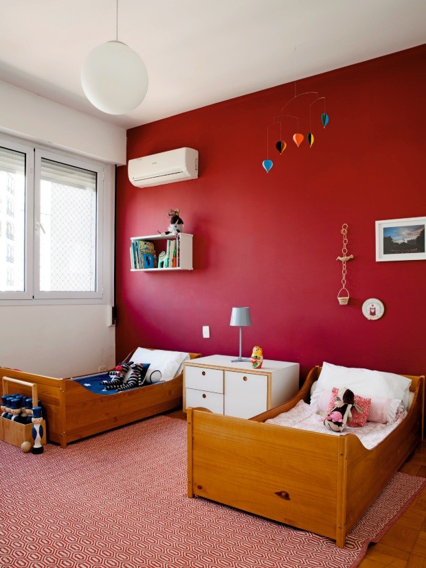 Quarto das crianças. Os filhos do casal dividem o mesmo dormitório, onde uma das paredes foi pintada em um tom de vermelho. Entre as camas há um pequeno móvel desenhado pelos arquitetos. Na parede, destaque para o bordado redondo (Foto: Maíra Acayaba / Editora Globo)