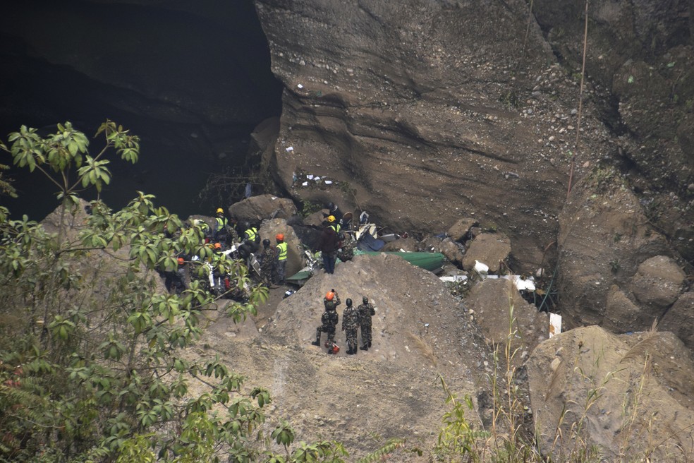 Equipe de resgate se arrisca em penhasco para tentar encontrar corpos das vítimas de acidente aéreo no Nepal — Foto: Krishna Mani Baral/AP