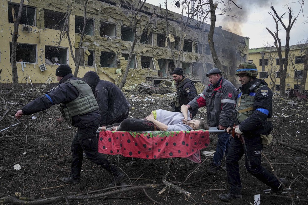 9 de março - Equipes de emergência e voluntários ucranianos carregam uma grávida ferida de uma maternidade danificada por um ataque aéreo em Mariupol, na Ucrânia. A mulher foi levada para outro hospital, mas não sobreviveu. — Foto: Evgeniy Maloletka/AP
