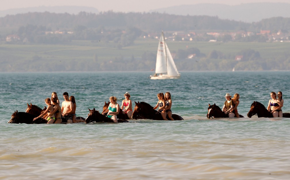 Banhistas cavalgam dentro da água do Lago Constança, perto de Güttingen, na Suíça. País também foi atingido por onda de calor neste verão europeu (Foto: Reuters/Arnd Wiegmann )