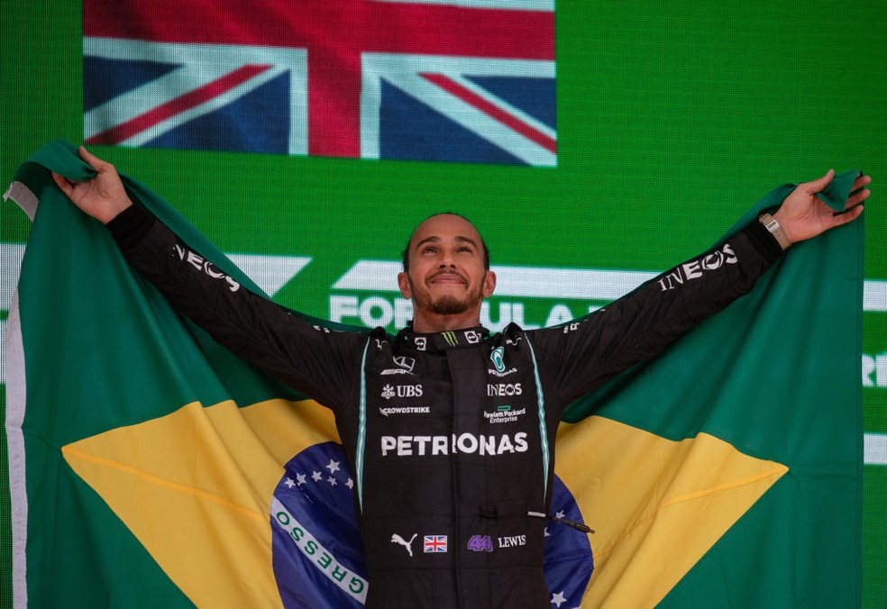 Lewis Hamilton celebra vitória no GP de São Paulo com bandeira do Brasil no pódio — Foto: Stringer/Anadolu Agency via Getty Images