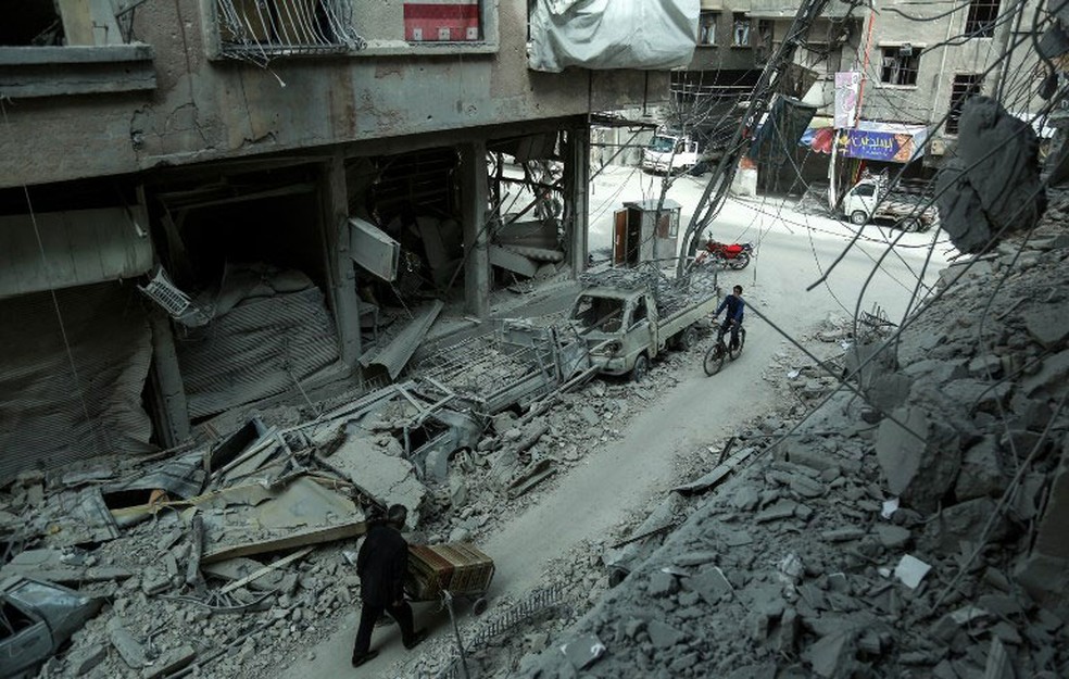 Foto mostra homem passando por destroÃ§os em Duma, na regiÃ£o de Guta Oriental, na quinta-feira (8)  (Foto: Hamza Al-Ajweh / AFP)