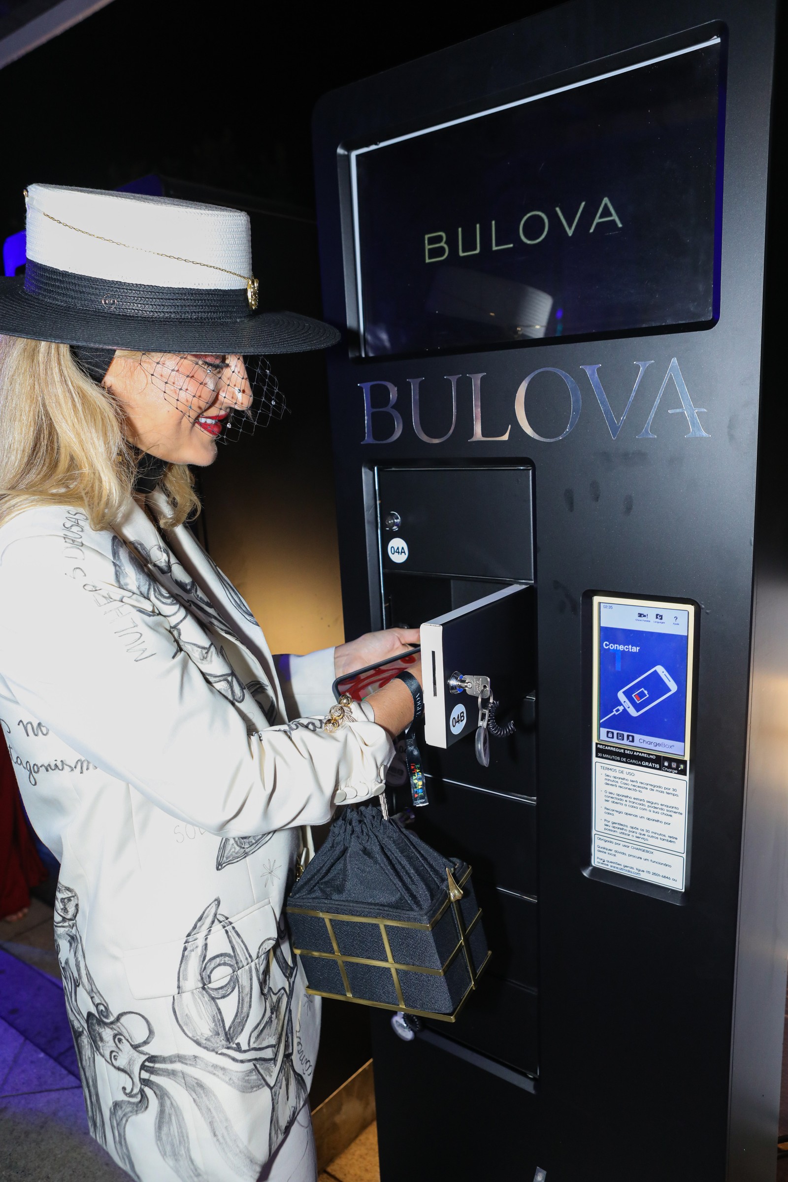 A designer Paola Vilas desbrava o carregamento de celular em instantes em uma estação da Bulova — Foto: Ricardo Cardoso 