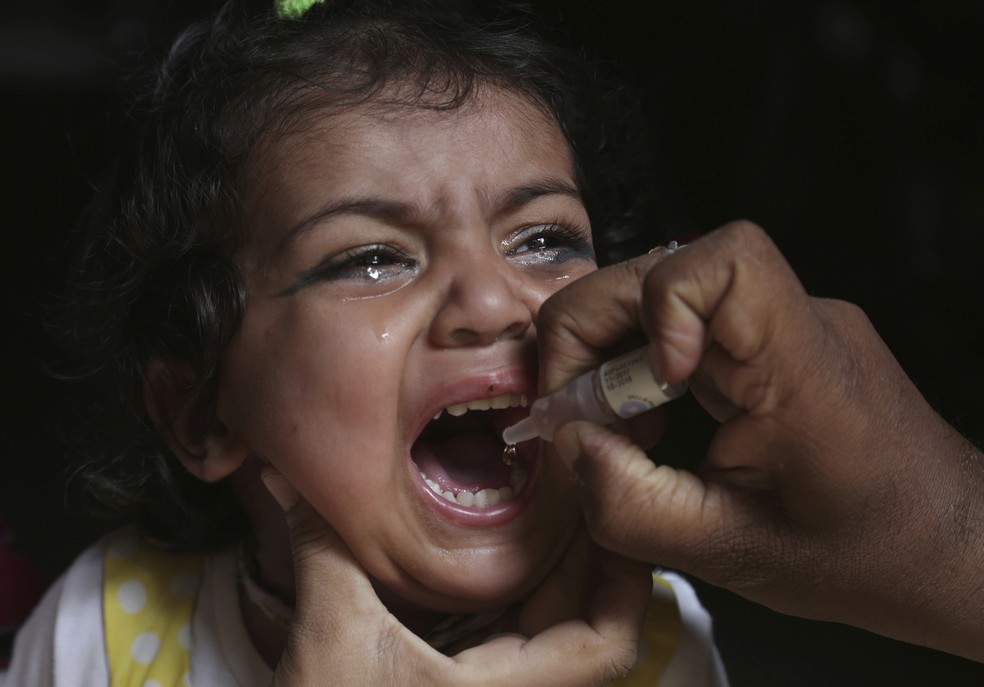 Um agente de saúde vacina uma criança contra poliomielite, em Lahore, no Paquistão. (Foto: K.M. Chaudary/AP)