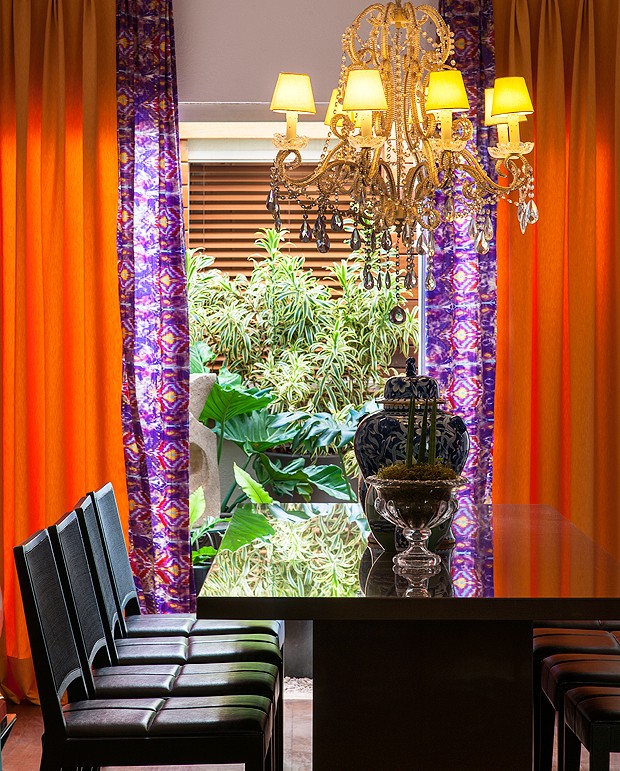 A sala de jantar tem vista para o jardim de inverno, o que deixa o espaço bem iluminado. A cortina laranja e roxa completa o ambiente (Foto: Divulgação/Romulo Fialdini)
