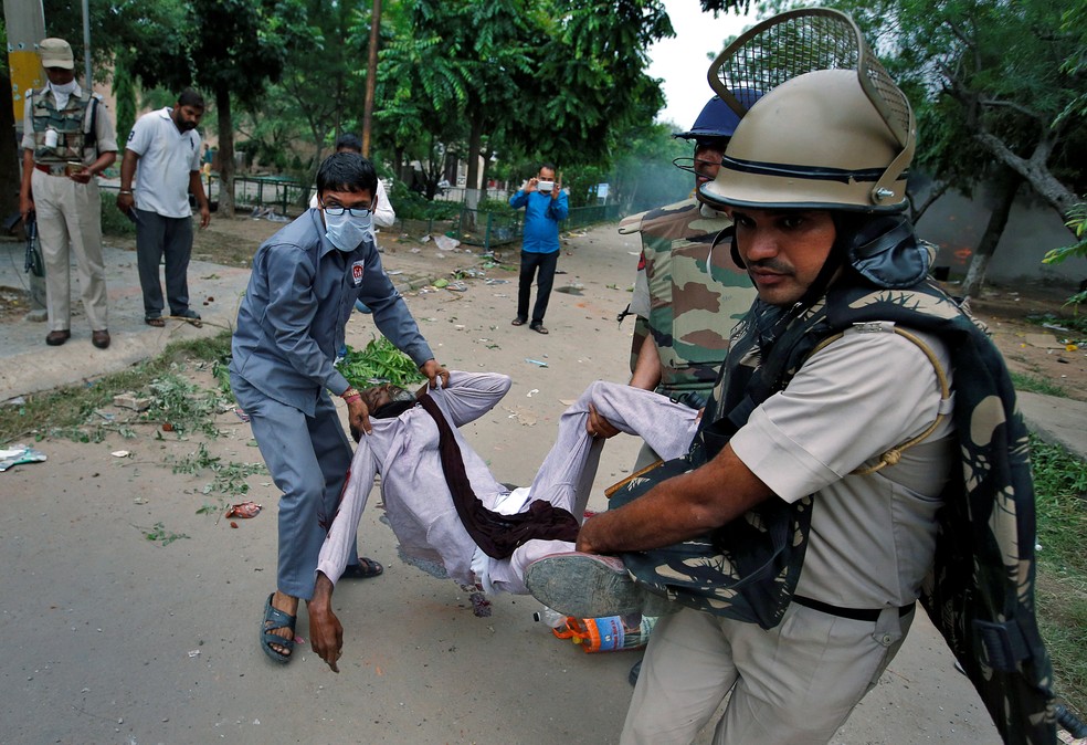 Membros das forças de segurança carregam homem ferido em combates na Índia (Foto: REUTERS/Cathal McNaughton)