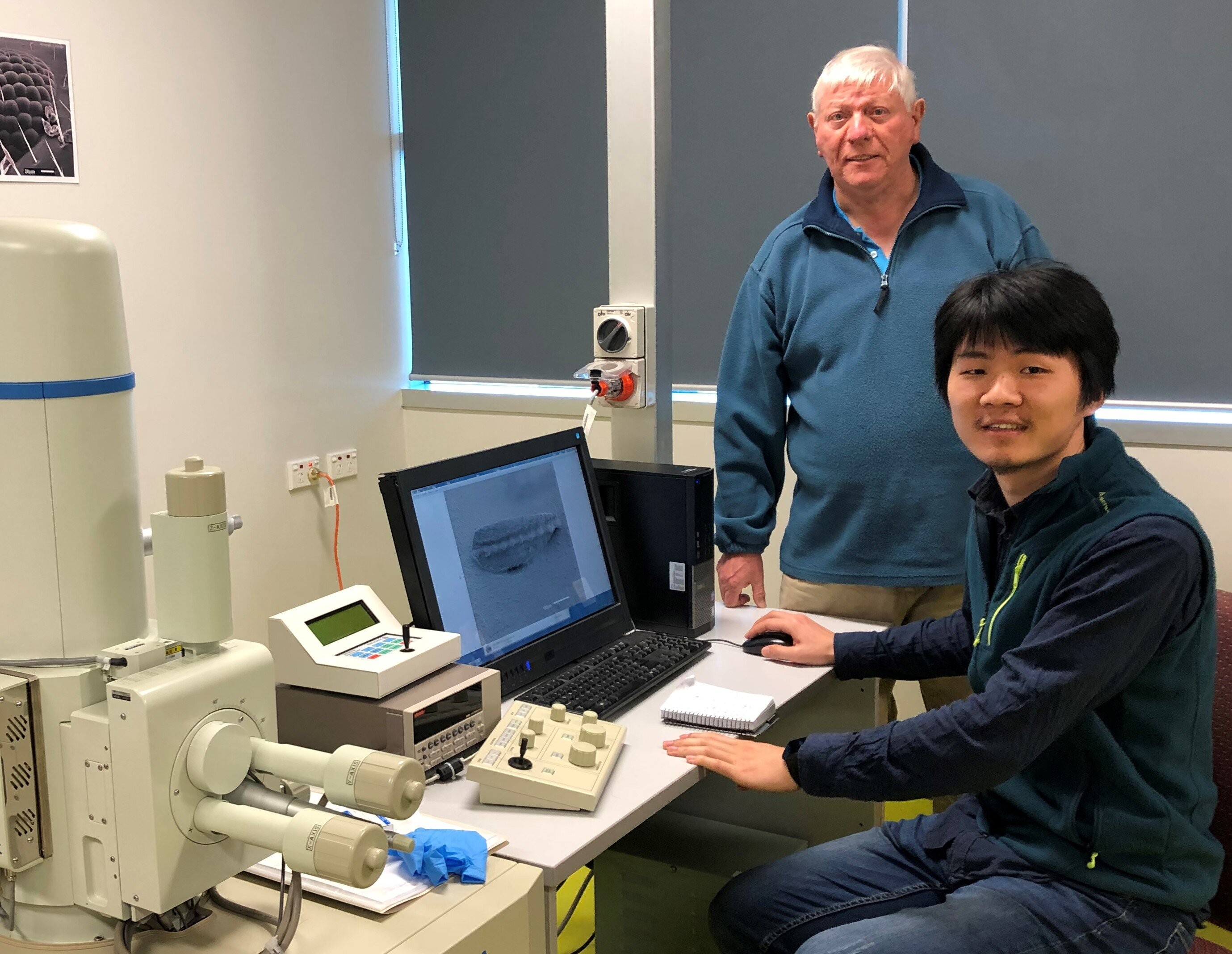 Ian Metcalfe (de pé) e Kui Wu, estudante da China University of Geosciences, estudam microfósseis com a ajuda de um microscópio (Foto: Universidade da Nova Inglaterra)