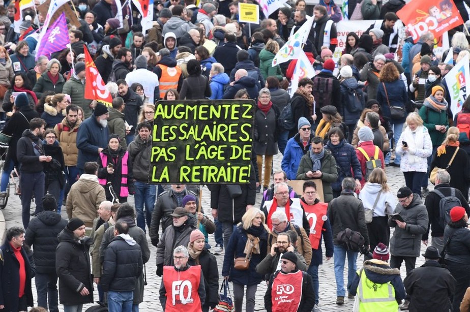 Manifestante segura cartaz em Paris: 'Aumente os salários, não a idade de aposentadoria'