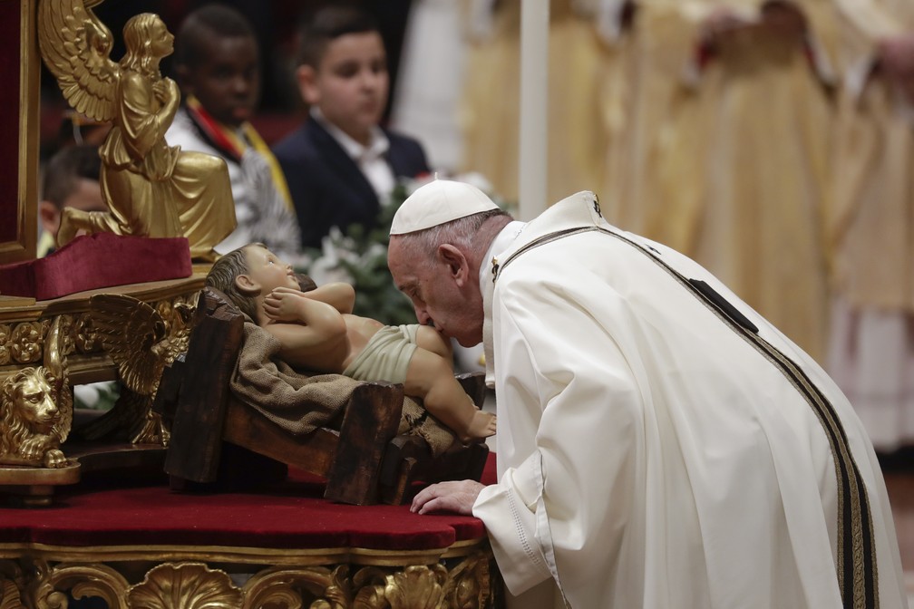 Papa Francisco beija uma estátua do menino Jesus enquanto celebra missa na véspera de Natal na Basílica de São Pedro, no Vaticano9. ( — Foto: AP Photo/Alessandra Tarantino