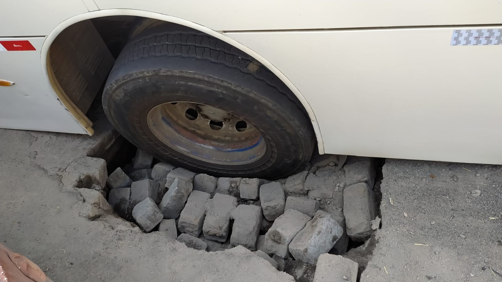 Ônibus fica com roda presa em buraco após parte do asfalto ceder em Valença