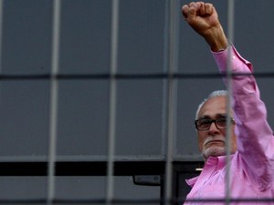 José Genoino ergue o braço à porta da sede da Polícia Federal de São Paulo, antes de se entregar para a prisão. Militantes de esquerda foram ao local para prestar apoio (Foto: Felipe Rau/Estadão Conteúdo)