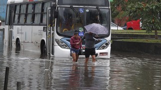 Passageiros caminham com água na altura do joelho devido às chuvas que atingiram o Rio — Foto: Fabiano Rocha / Agência O Globo
