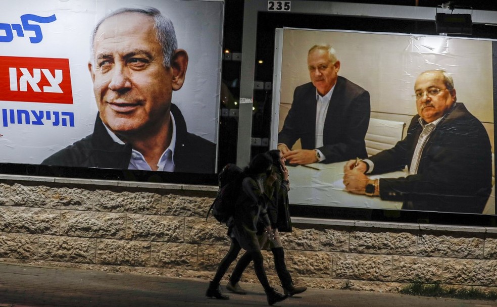 Cartaz da campanha de Benjamin Netanyahu (à esquerda) ao lado de outdoor que mostra Benny Gantz sentado ao lado de líder de partido pró-árabe, em foto de fevereiro de 2020 — Foto: Ahmad Gharabli/AFP