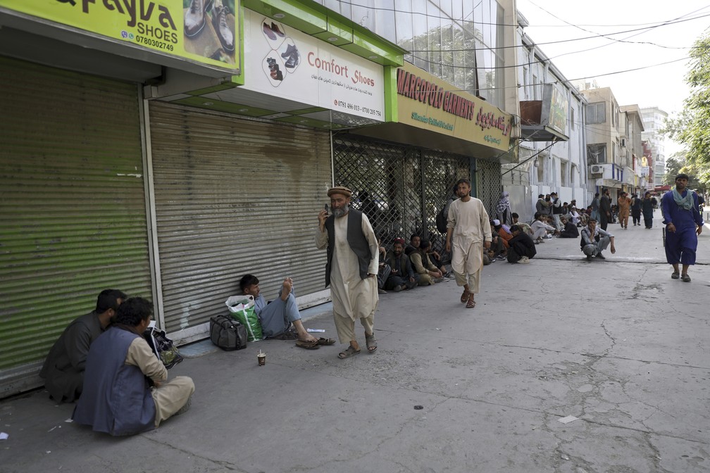 O comercio de Cabul, capital do Afeganistão, fechado, enquanto a população espera em fila para sacar dinheiro no banco — Foto: ASSOCIATED PRESS