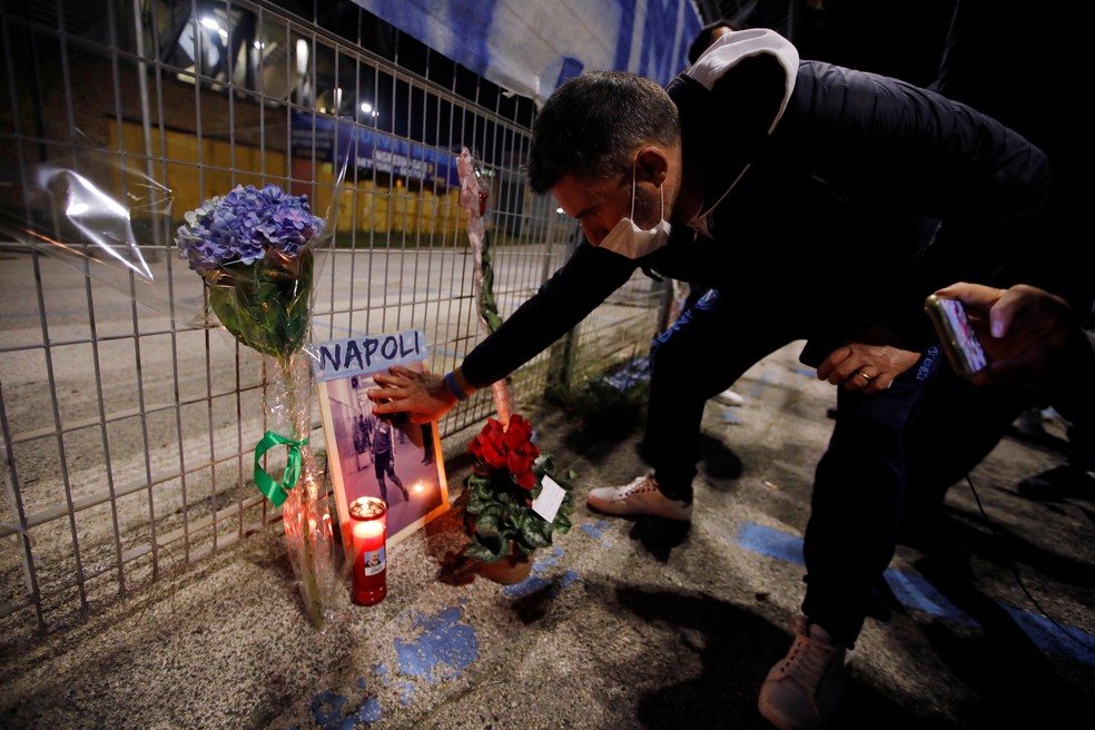 Homem faz homenagem ao astro do futebol argentino Diego Maradona, morto nesta quarta-feira (25), do lado de fora do estádio San Paolo em Nápolis, na Itália — Foto: Ciro De Luca/Reuters
