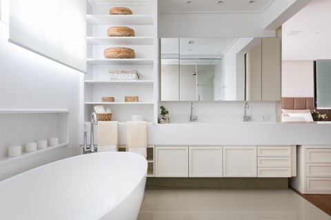 A arquiteta Vivi Cirello idealizou esse banheiro de casal de 9 m² com uma base neutra e clara. As prateleiras, criadas como uma estante, foram pensadas para a moradora colocar sais de banho e velas