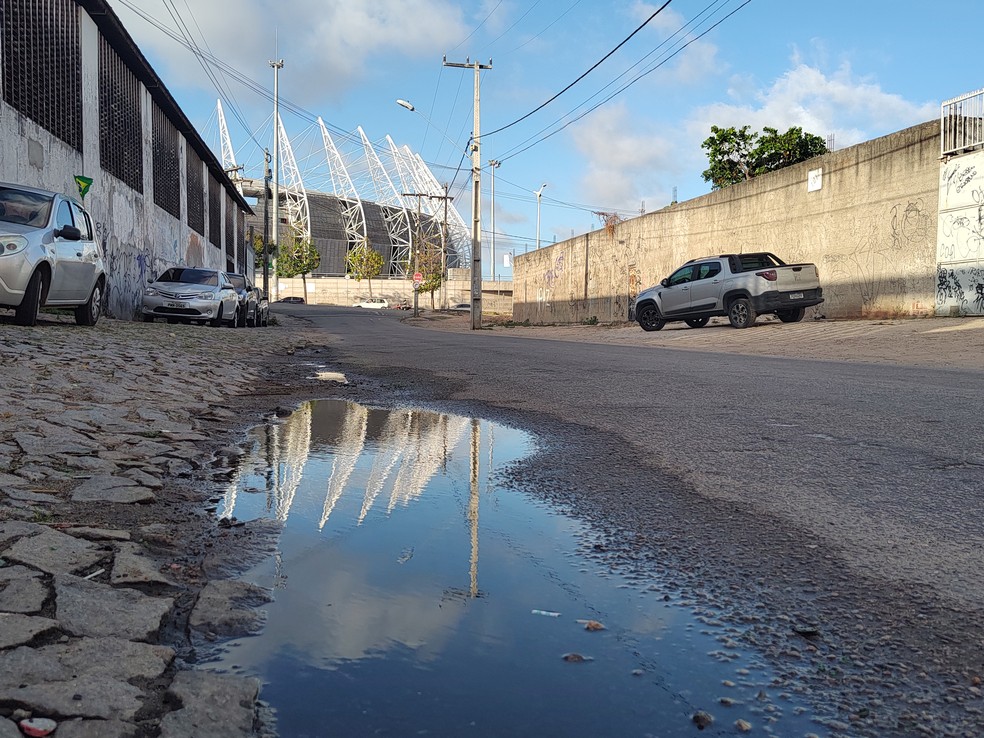 Imagem da arena espelhada em água de esgoto que corre a céu aberto na Rua Crisanto Arruda — Foto: Paulo Martins/g1 CE