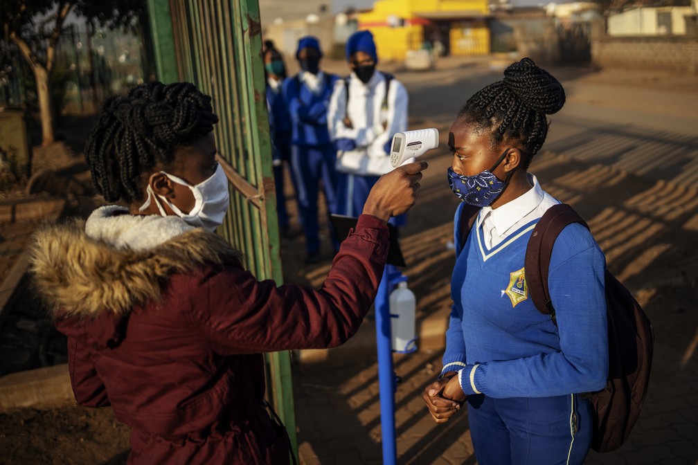 Alunos de escola em Tembisa, na África do Sul, usam máscaras e têm a temperatura do corpo checada na volta às aulas presenciais nesta segunda-feira (8) — Foto: Michele Spatari / AFP