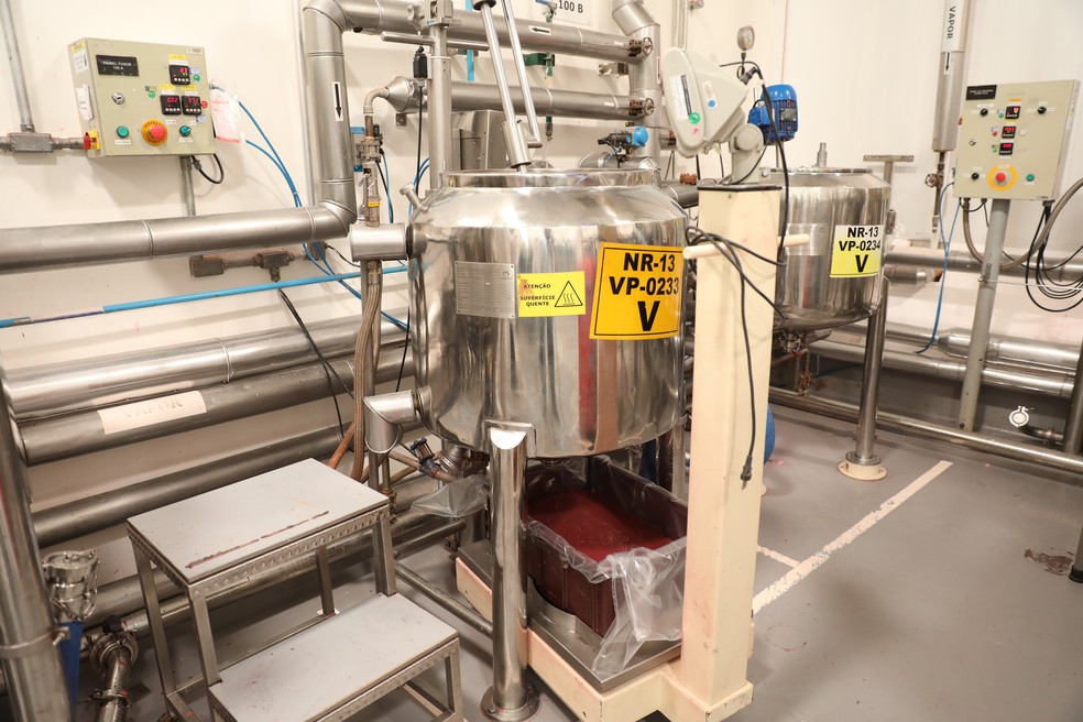 Mistura é retirada pela parte de baixo do fusor, caindo sobre uma folha de plástico em um recipiente retangular (Foto: Celso Tavares/G1)