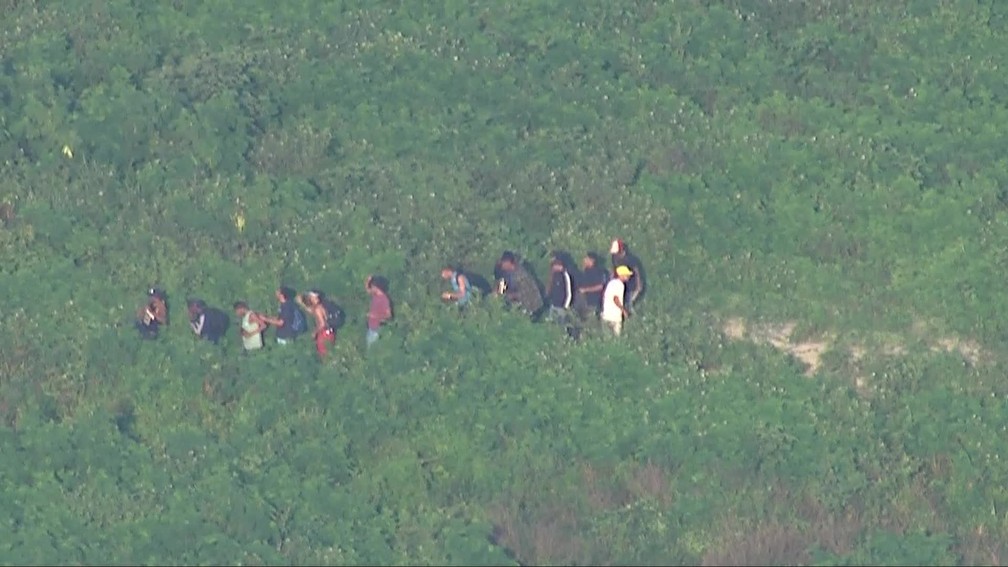 Homens fogem por área de mata na Cidade de Deus — Foto: Reprodução/TV Globo